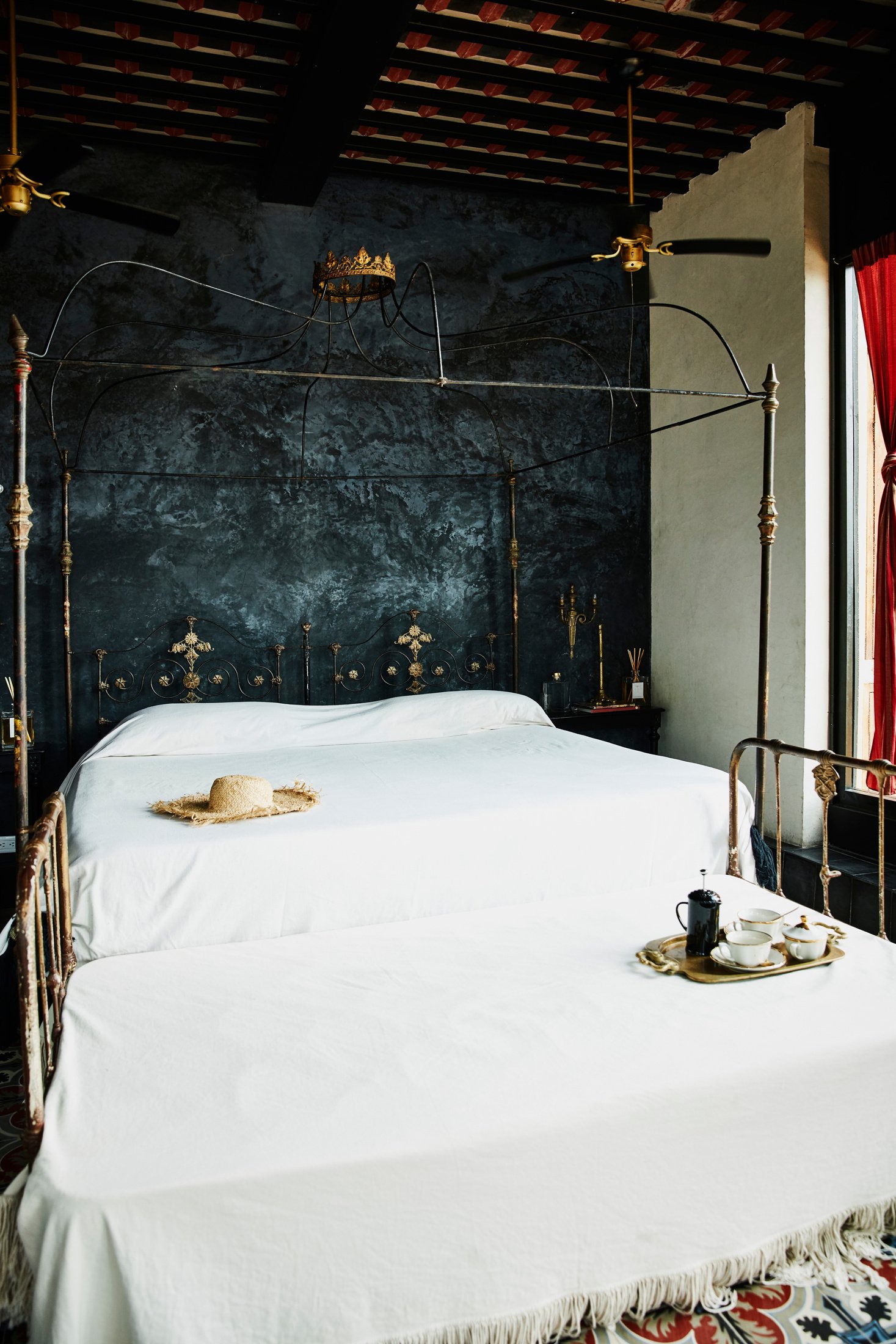 Coffee service and sun hat sitting on bed in room in boutique hotel